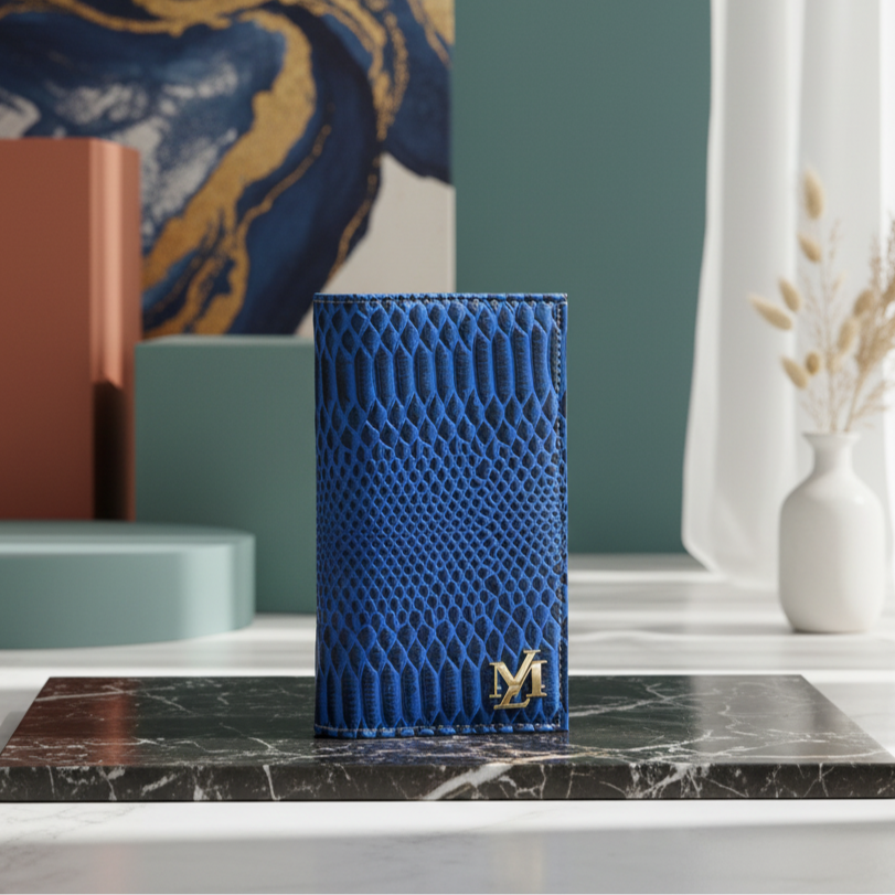Blue textured phone case with a gold logo on a marble surface, with a decorative wall and vase in the background.